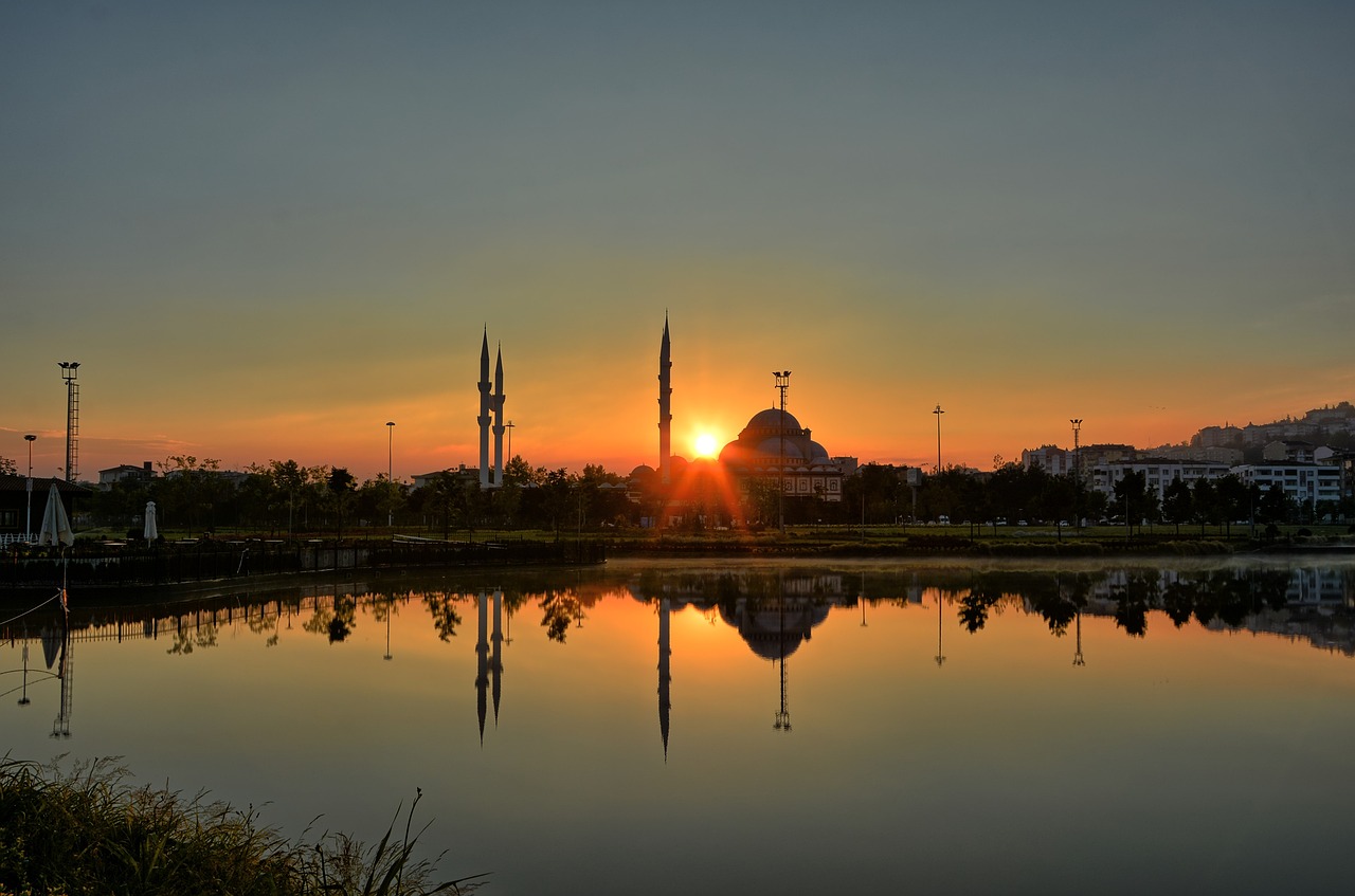 Sunset over the Grand Mosque (Ulu Cami) in Bursa, Turkey, with its reflection in a calm lake.