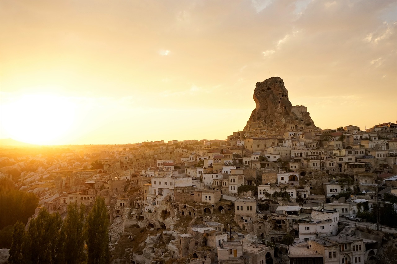 A breathtaking view of Nevsehir's iconic fairy chimneys and ancient rock formations at sunset in Cappadocia.