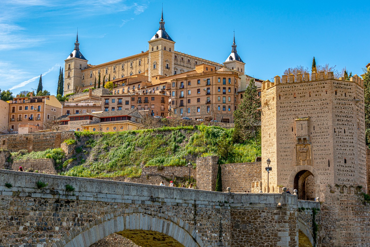 Toledo travel guide: View of the Alcázar of Toledo, a prominent fortress standing majestically on a hilltop, with ancient stone walls and medieval architecture in the foreground.