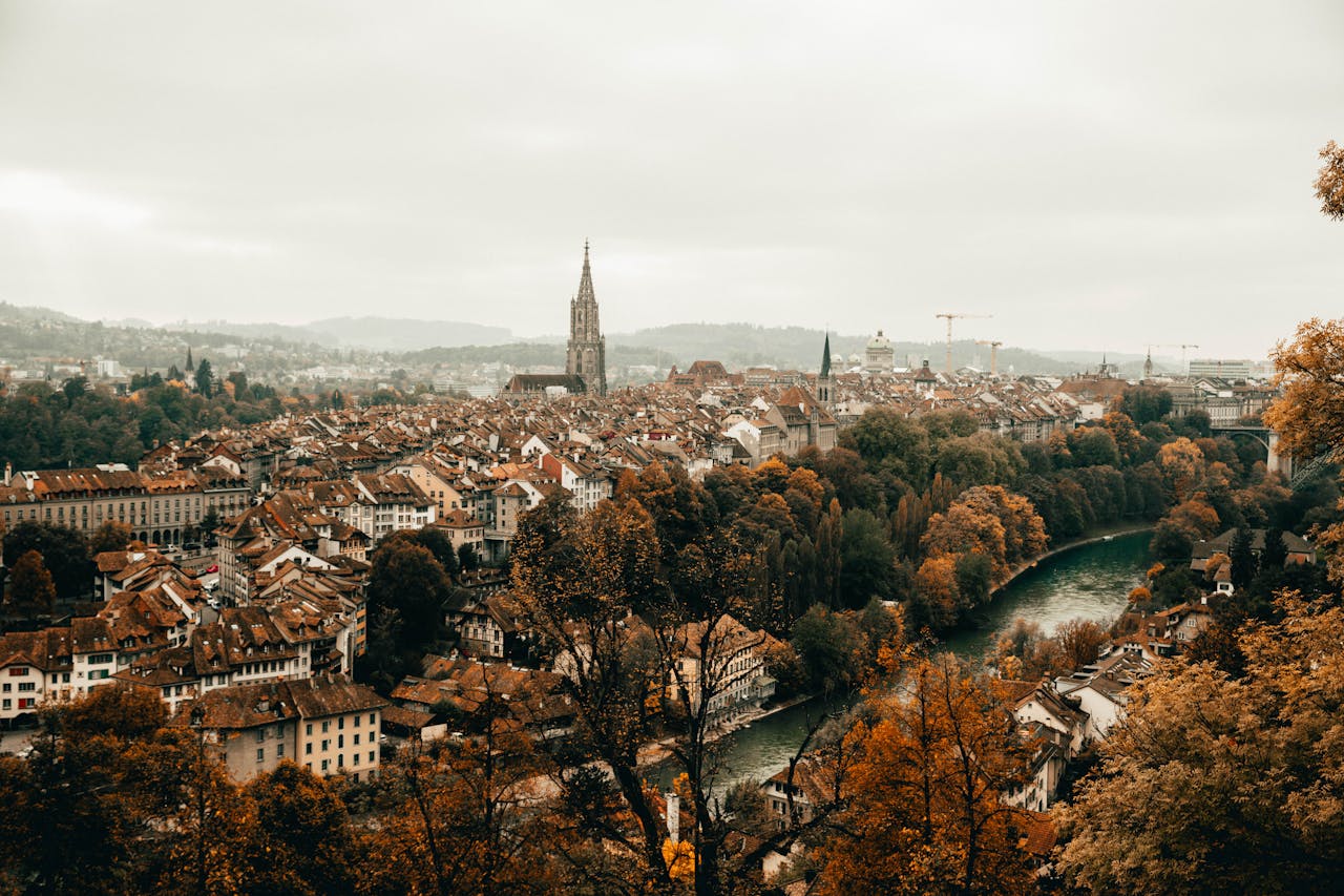 Bern Travel Guide: A panoramic view of Bern, Switzerland, featuring the Old Town with its medieval architecture and the Aare River flowing through the city.