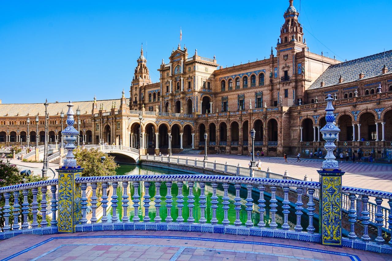 Seville travel guide: View of the stunning Plaza de España in Seville, featuring its beautiful architecture and vibrant tilework under a clear blue sky.