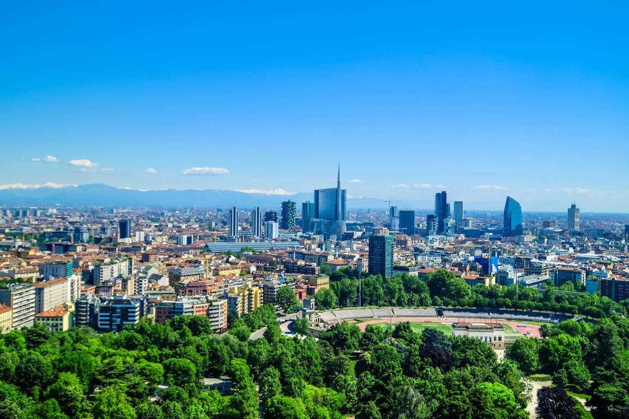 A panoramic view of Milan, Italy, showcasing the city’s modern skyline with green parks in the foreground