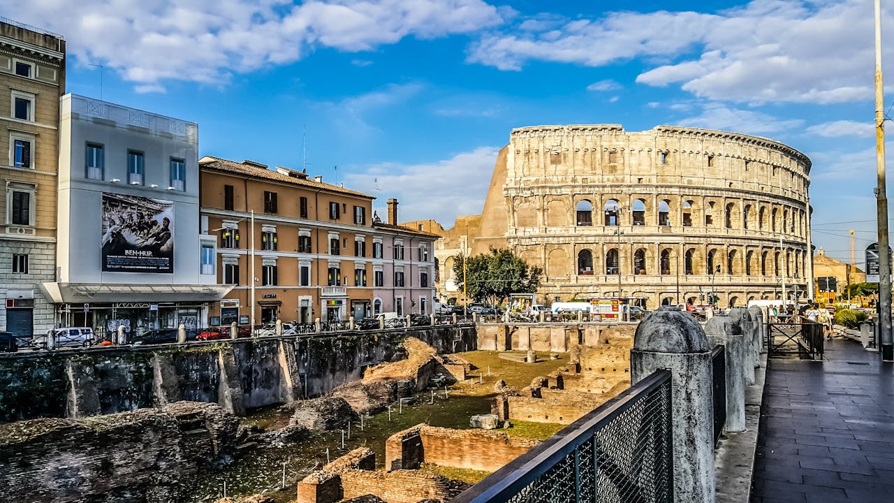 A stunning view of the Colosseum in Rome, Italy, with the surrounding historic buildings under a blue sky