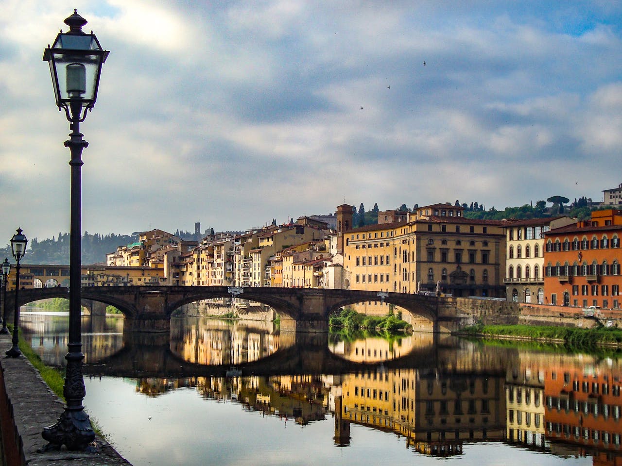 A scenic view of the Arno River with historic buildings and a bridge in Florence, Italy