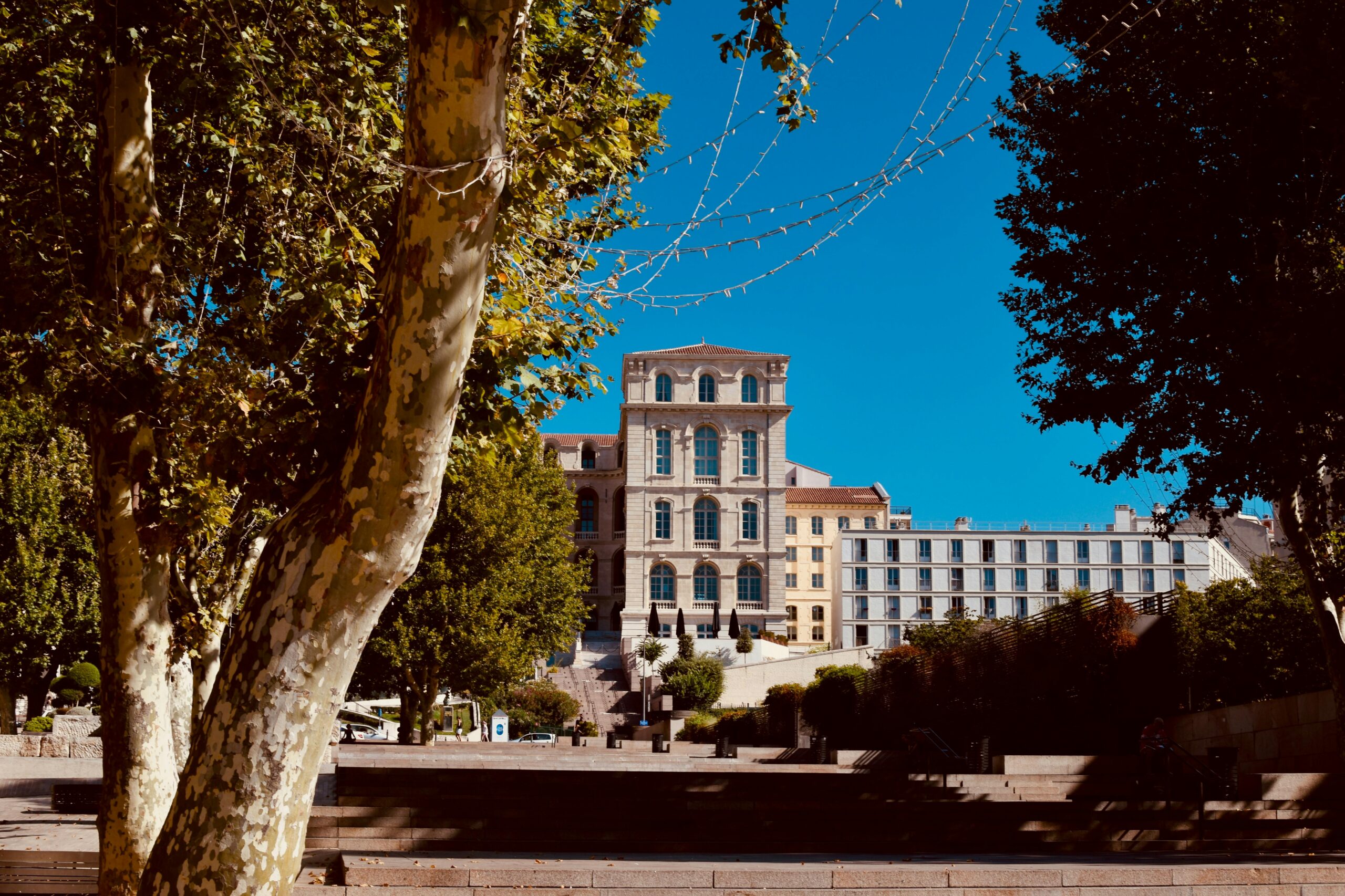 A scenic view of a historic building framed by trees in Marseille, France, on a sunny day